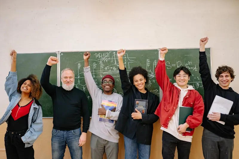 Diverse students and tutor celebrating academic achievement in front of chalkboard with mathematical equations
